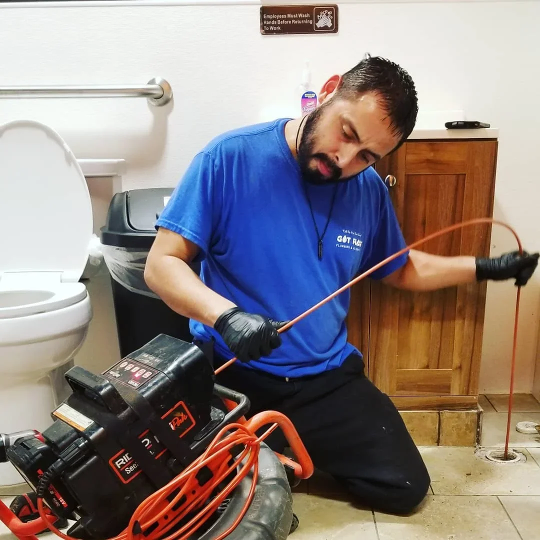 Plumber using motorized drain auger to clean bathroom drain line with diagnostic equipment