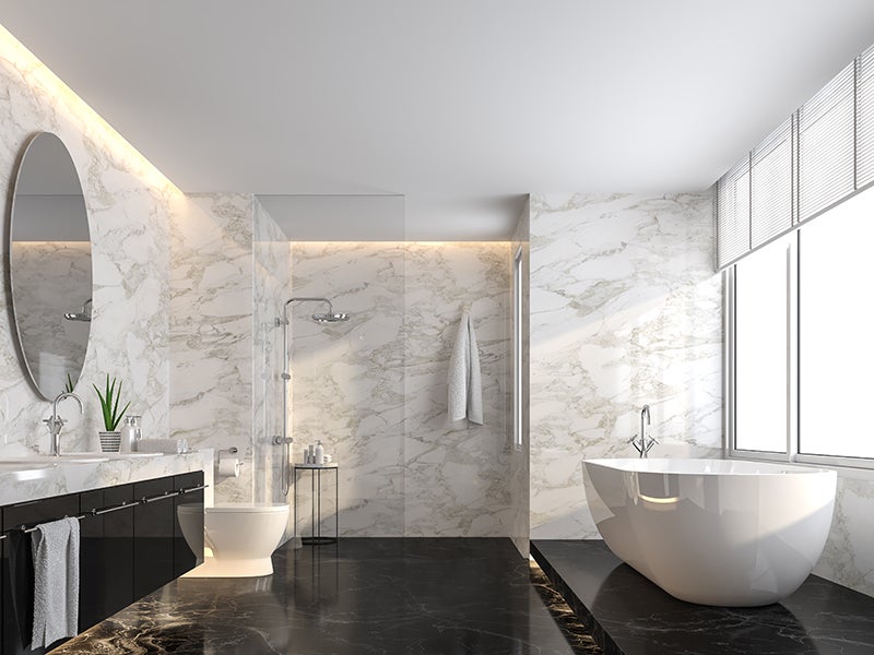 Luxury bathroom with marble walls, black floor, freestanding tub, and shower