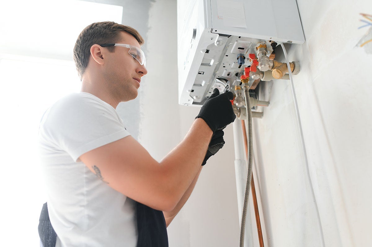 Plumber installing or repairing a wall-mounted boiler or water heater