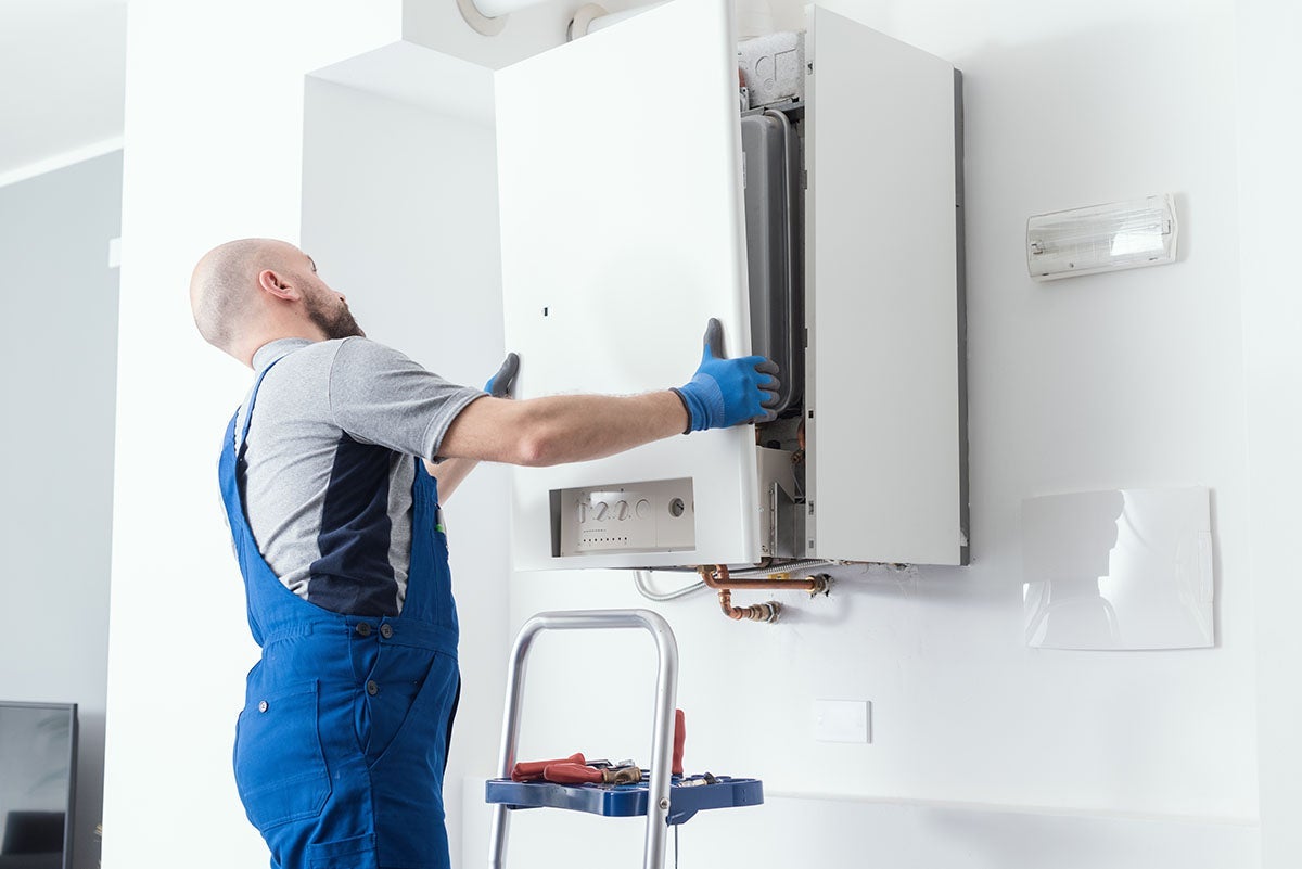 Technician installing or repairing a wall-mounted gas boiler or water heater
